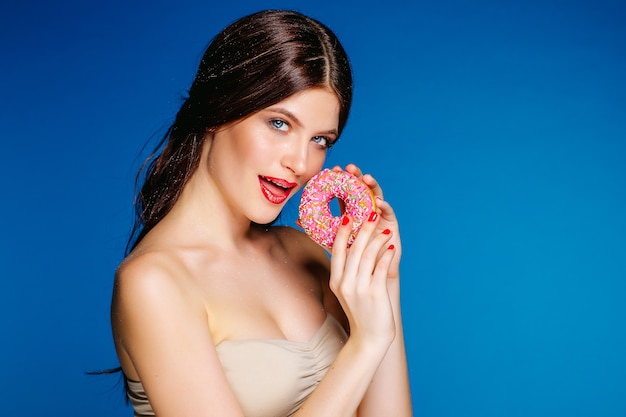 Porträt der schönen Frau mit Donut lokalisiert auf blauem Hintergrund