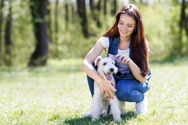 Porträt der schönen Frauen, die ihren Hund im Freien kämmen