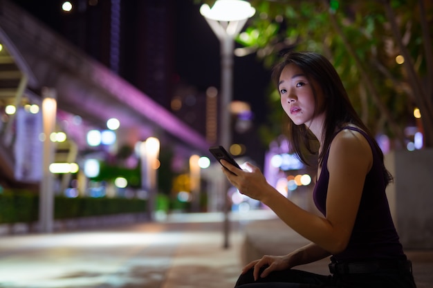 Porträt der schönen jungen chinesischen Frau im Freien bei Nacht