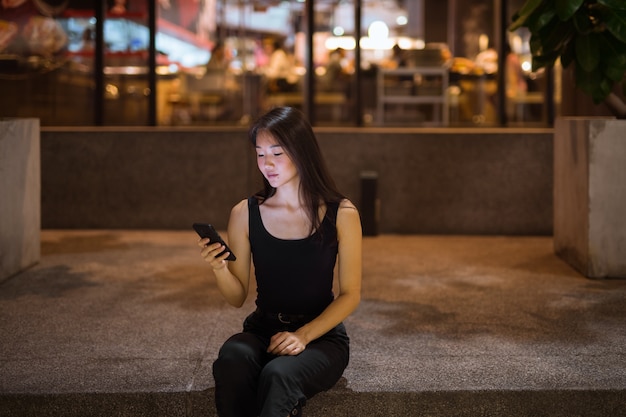 Porträt der schönen jungen chinesischen Frau im Freien bei Nacht