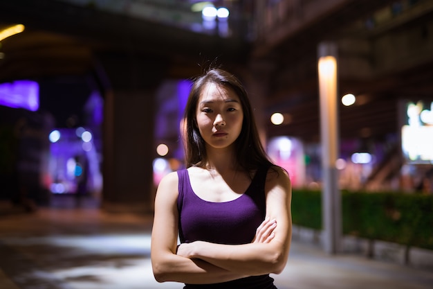 Porträt der schönen jungen chinesischen Frau im Freien bei Nacht
