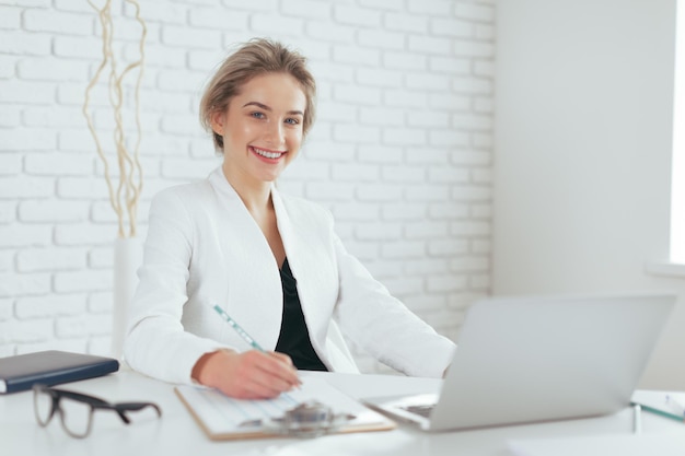 Porträt der schönen jungen Frau, die im Büro arbeitet