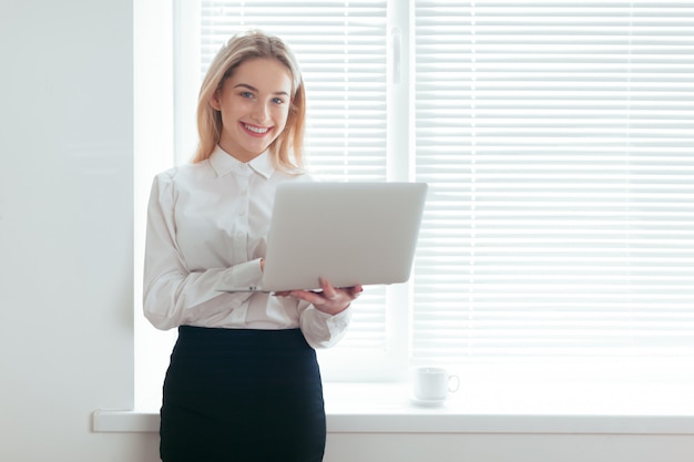 Porträt der schönen jungen Frau, die im Büro arbeitet.