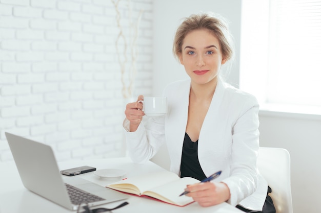 Porträt der schönen jungen Frau, die im Büro arbeitet.