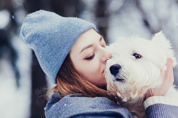 Porträt der schönen jungen Frau mit Hund im Winter