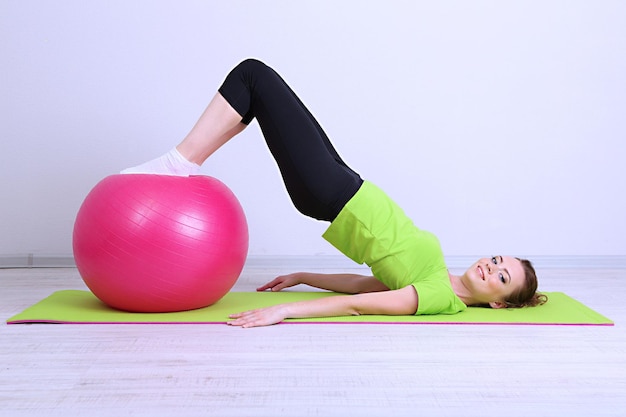 Porträt der schönen jungen Frau übt mit Gymnastikball aus