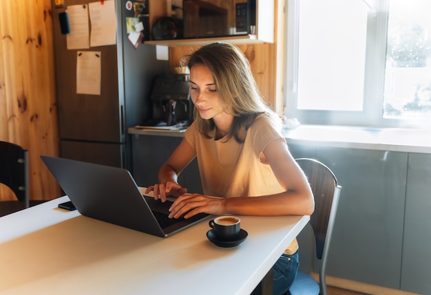 Porträt der schönen jungen Geschäftsfrau, die am Laptop im Heimbüro arbeitet