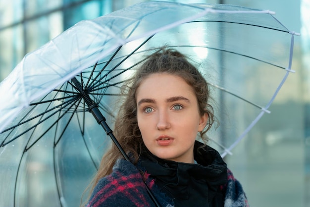 Porträt der schönen nachdenklichen jungen Frau mit transparentem Regenschirm Sonniger Tag Attraktives Mädchen zu Fuß in der Stadt