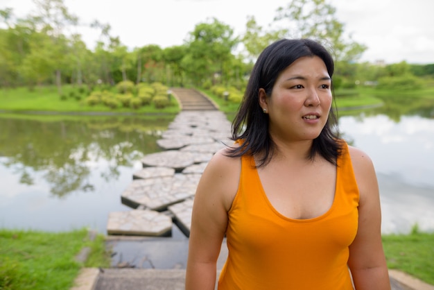 Porträt der schönen übergewichtigen asiatischen Frau, die am Park in der Stadt von Bangkok, Thailand entspannt