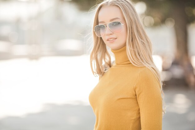 Porträt der sehr attraktiven jungen Frau im Freien. Schöne blonde Dame am städtischen Hintergrund. Stilvolles weibliches Nahaufnahmeporträt.