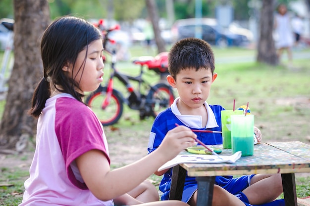 Porträt der sommermalerei des kleinen mädchens und des jungen im freien im park