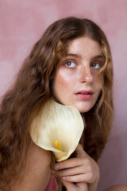 Porträt der sommersprossigen Frau, die eine Blume hält