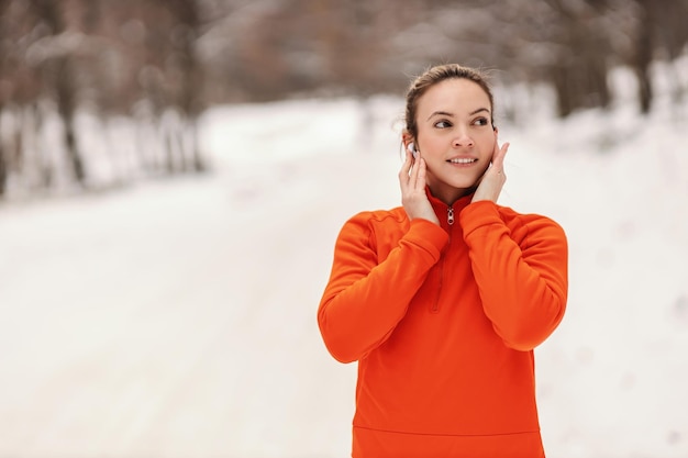 Porträt der Sportlerin Kopfhörer setzen Winter Fitness gesundes Leben Musikspaß