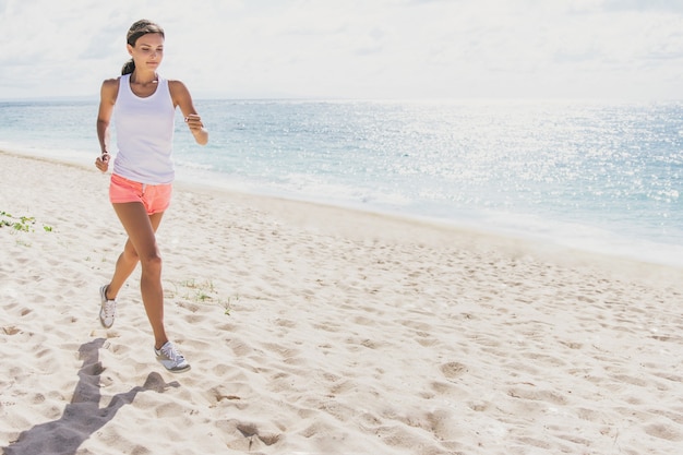 Porträt der sportlichen Frau, die am Strand joggt