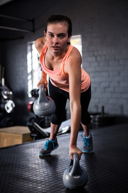 Porträt der sportlichen jungen Frau, die Kettlebell hält