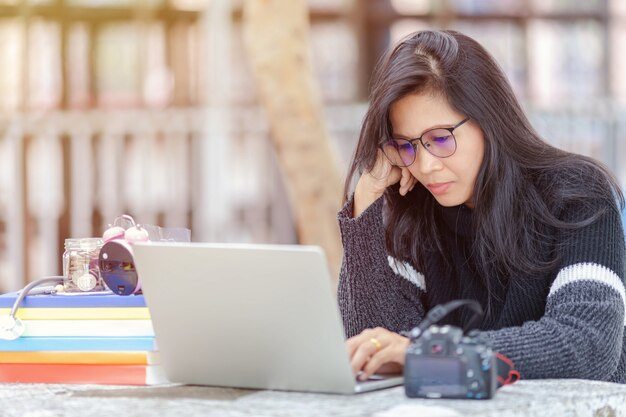 Porträt der Studentin sitzend am Park und Laptop verwendend