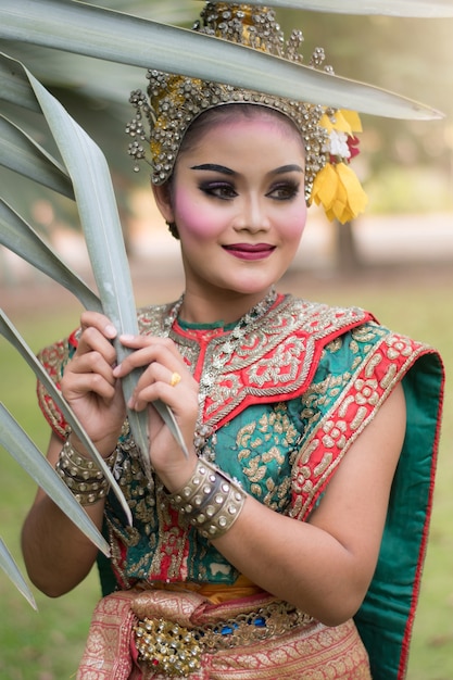 Porträt der thailändischen jungen Dame, die thailändisches Trachtenkleid im Garten trägt