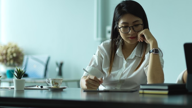 Porträt der Unternehmerin, die mit Büromaterial auf Schreibtisch arbeitet