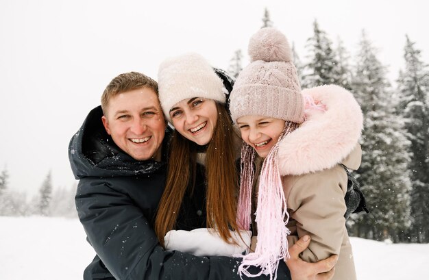 Porträt der verspielten glücklichen Familie im Winterwald. Mutter, Vater und Tochter spielen mit Schnee. Genießen Sie die gemeinsame Zeit. Familienkonzept