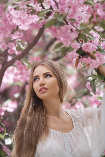 Porträt der zarten Frau gegen die Sakura-Blume