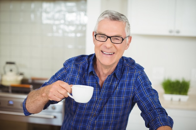 Porträt des älteren Mannes, der Tasse schwarzen Tee hat