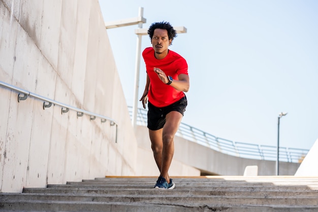 Porträt des Afroathletenmannes, der draußen läuft und Übung tut.