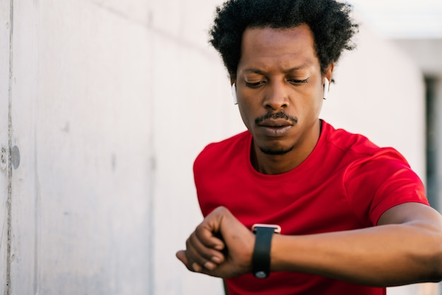 Porträt des Afroathletenmannes, der Zeit auf seiner intelligenten Uhr prüft. Sport und gesunder Lebensstil Konzept.