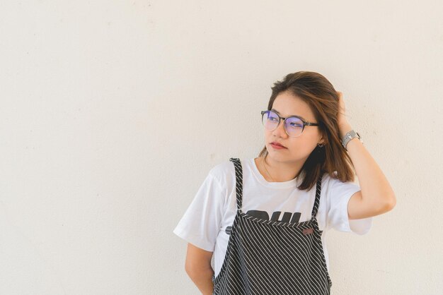 Porträt des asiatischen schönen Mädchens trägt eine Brille auf weißem Wandhintergrund