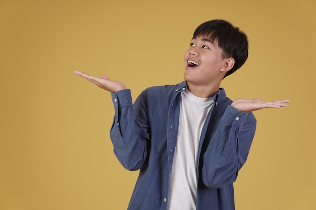 Porträt des aufgeregten glücklichen gutaussehenden jungen asiatischen Mannes, der beiläufig lächelnd mit offener Handgeste isoliert gekleidet gekleidet ist