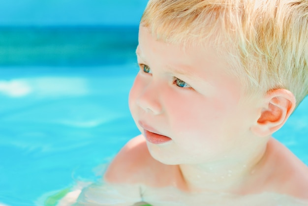 Porträt des Babys genießend, im aufblasbaren Pool schwimmend