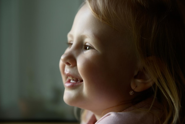 Porträt des Babys hautnah. Europäisches Baby mit goldenen Ohrringen.