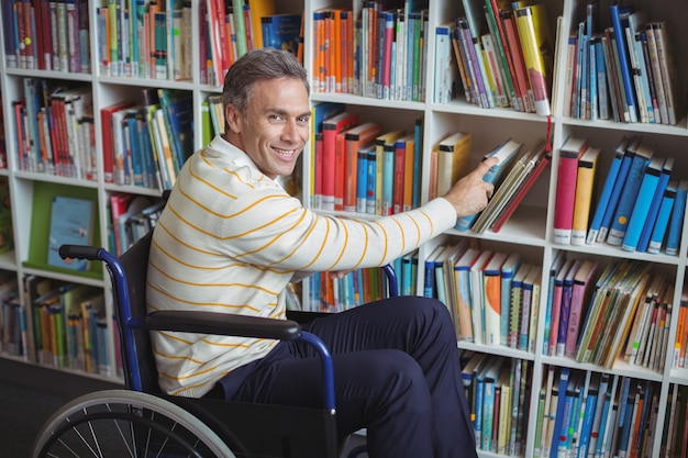 Porträt des behinderten Schullehrers, der Buch in der Bibliothek auswählt