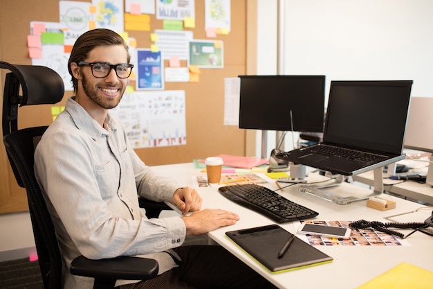 Porträt des designers, der am kreativen büro sitzt