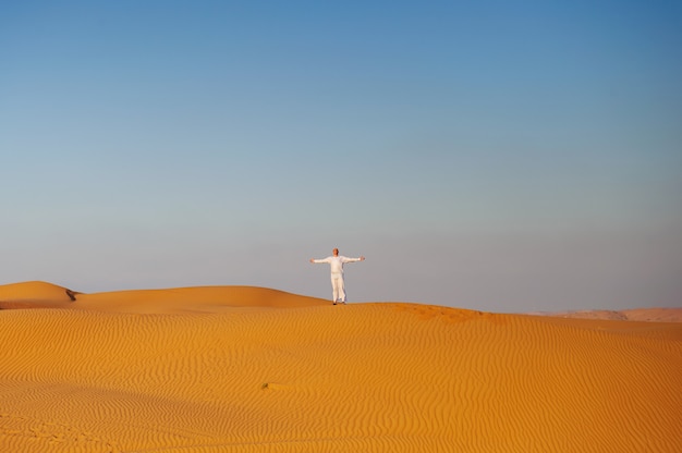 Porträt des durstigen arabischen Mannes auf einer Mitte der gelben Wüste.