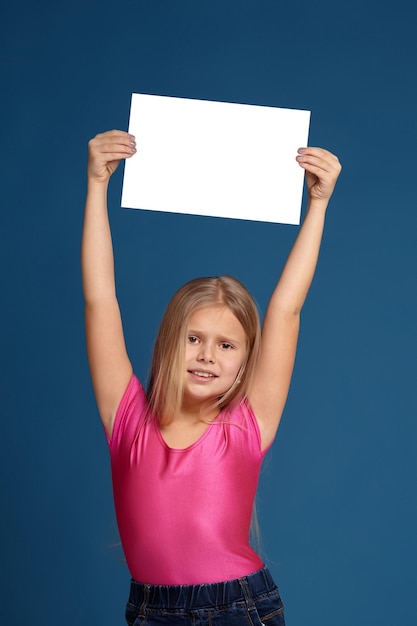 Porträt des entzückenden emotionalen kleinen Mädchens auf blauem Hintergrund