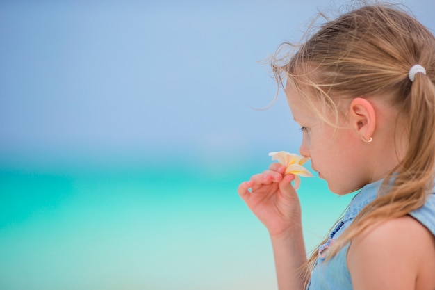 Porträt des entzückenden kleinen Mädchens mit Blume Frangipani auf Strandsommerferien