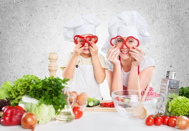 Porträt des entzückenden kleinen Mädchens und ihrer Mutter, die zusammen kochen