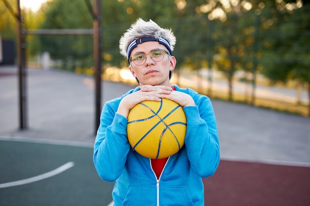 Porträt des ernsten jungen kaukasischen Jungen mit Basketballball in den Händen