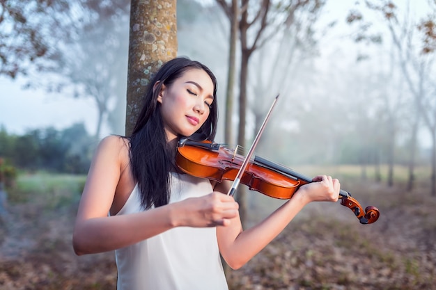 Porträt des Frauenkleides im weißen langen Kleid, das die Violine, die Weichzeichnung und den Weinleseton spielt