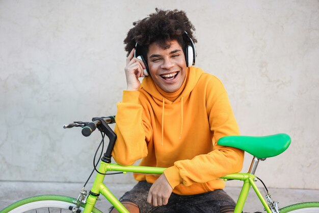 Porträt des fröhlichen jungen Teenager-Bikerjungen, der eine Musikwiedergabeliste hört - Fokus auf Gesicht