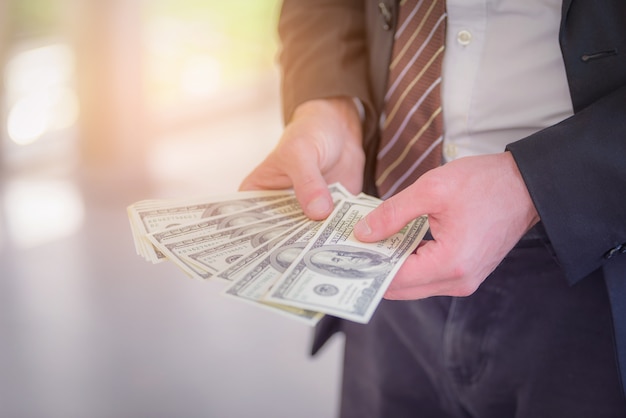 Porträt des Geschäftsmannes Geld-Bargeld-Dollar in den Händen halten