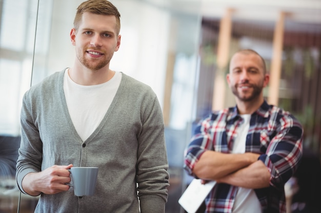 Porträt des Geschäftsmannes Kaffeetasse im kreativen Büro halten