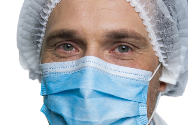 Porträt des Gesichts des Chirurgen. Nahaufnahme des Gesichts des Arztes in Atemschutzmaske isoliert auf weißer Wand.