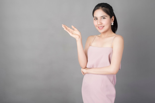 Porträt des gesunden schönen Mädchens im rosa Kleid auf grauem Hintergrund, Atelieraufnahme