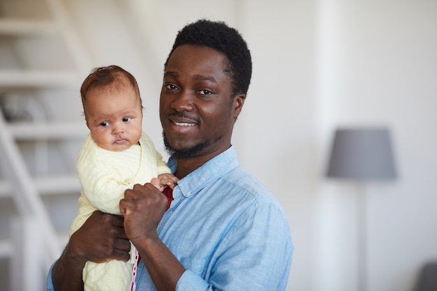 Porträt des glücklichen afrikanischen Vaters, der Baby auf seinen Händen hält und lächelt