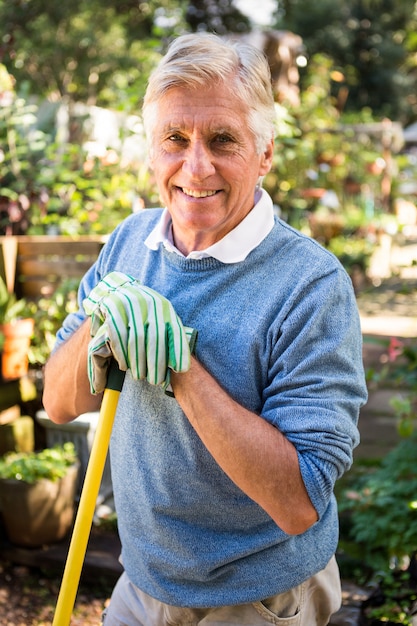 Porträt des glücklichen Gärtners mit Werkzeug am Garten