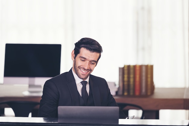 Porträt des glücklichen Geschäftsmannes, der am Schreibtisch sitzt