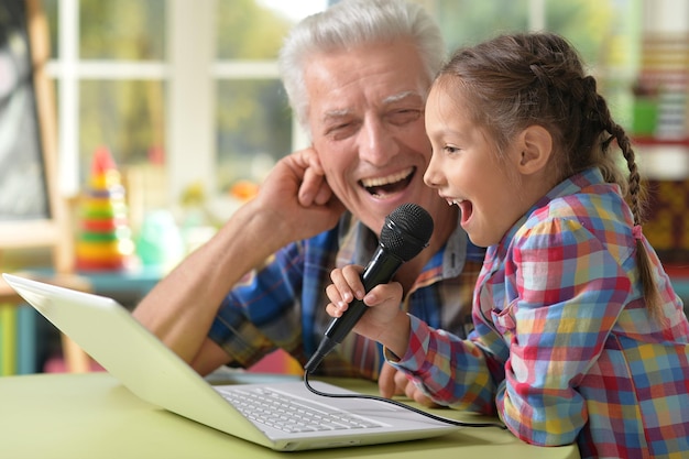 Porträt des glücklichen Großvaters und des Kindes, das Karaoke singt