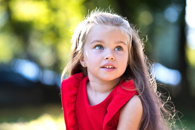 Porträt des glücklichen hübschen Kindermädchens, das draußen lächelt und warmen sonnigen Sommertag genießt.