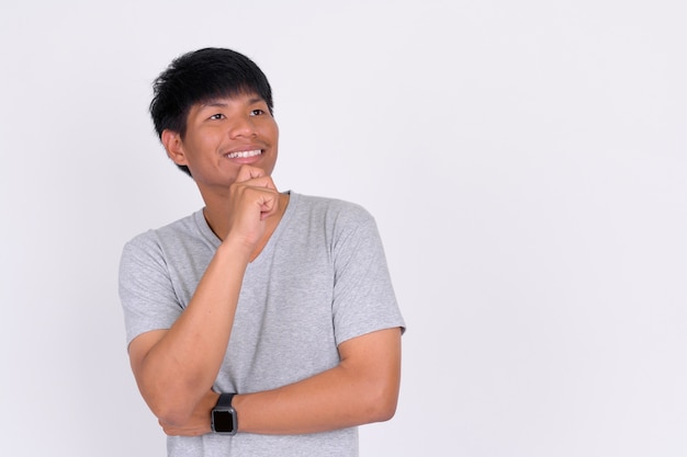 Porträt des glücklichen jungen asiatischen Mannes, der denkt und schaut